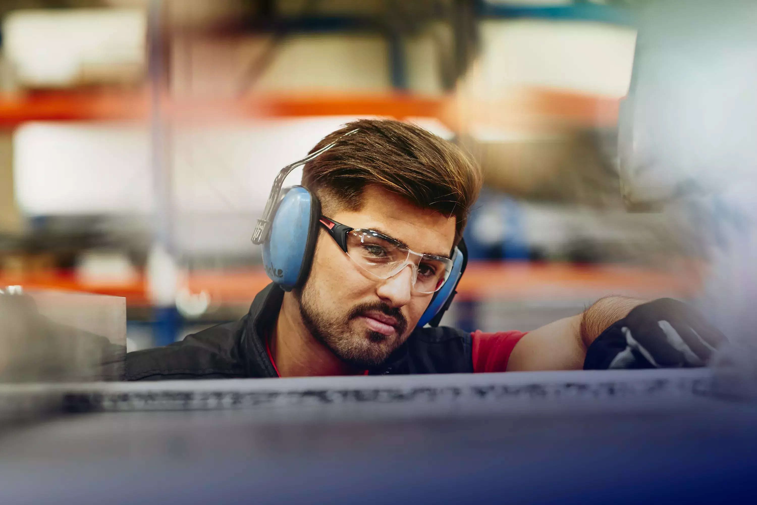 male wearing protective ear covers, safety gloves and safety glasses on a production site