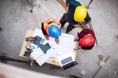 Three architects examining the blueprints on construction site