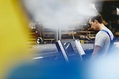 Male blue-collar worker operating a device. Caucasian man. Looking at a display with buttons and switches. Tech environment. Primary color yellow. Secondary color blue. 